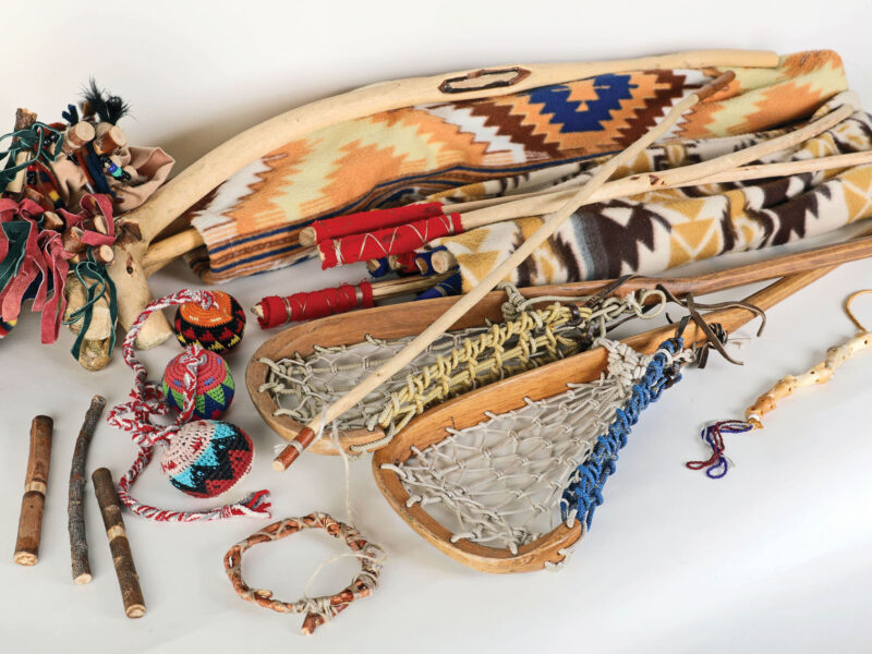 A display of Native American artifacts, including a beaded cradleboard, a dreamcatcher, and leather accessories.