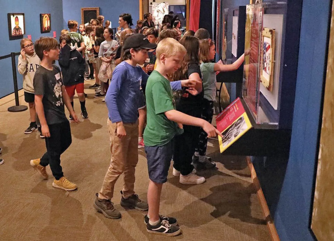 A group of elementary school students standing in a museum gallery, looking at an educational exhibit during a school visit to Museum of the Rockies.
