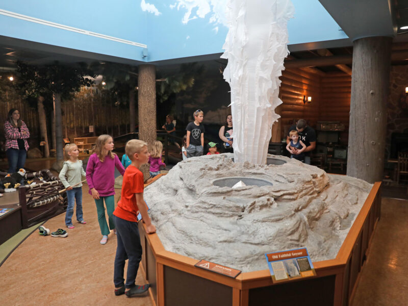Children gathered around a replica model of the Old Faithful geyser in the "Explore Yellowstone" exhibition at Museum of the Rockies, as it mimic's releasing tall plume of water which was formed from white fabric.