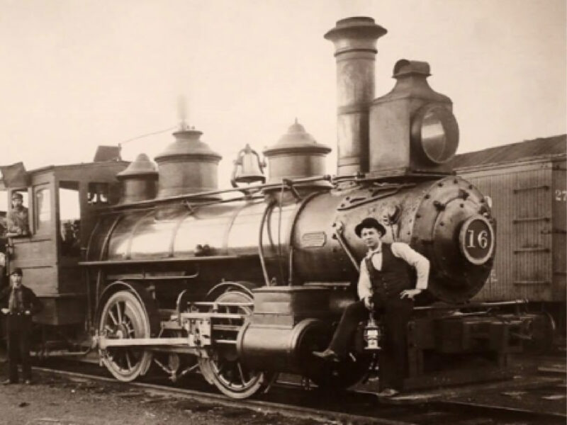 A historical black-and-white photograph of a Northern Pacific Railroad steam engine, featuring a railroad worker posing in front of the locomotive numbered 16.